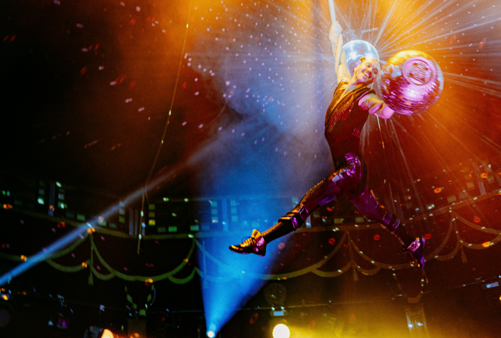 Male rope artist performing a disco ball rope act - one arm grip hang