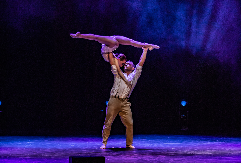Acrobatic duo performing a flexible trick on stage 