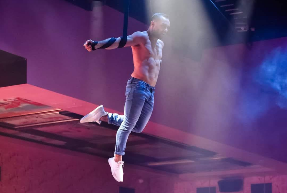 Male straps artist performing roller ups on stage
