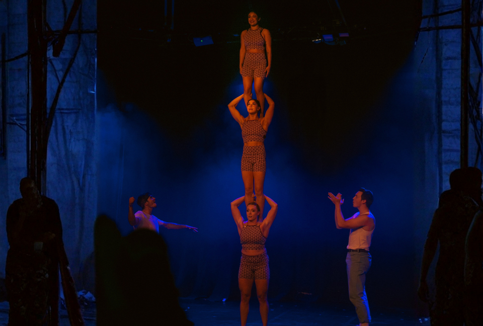 Circus acrobats performing a three high stack on stage